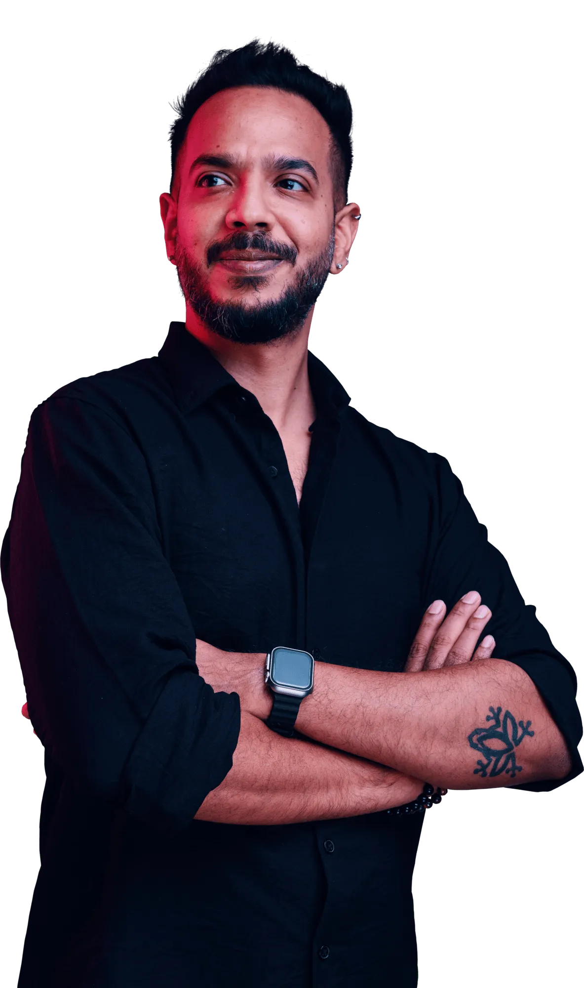 Bearded man in a black shirt with a forearm tattoo and a smartwatch stands with arms crossed against a dark background.