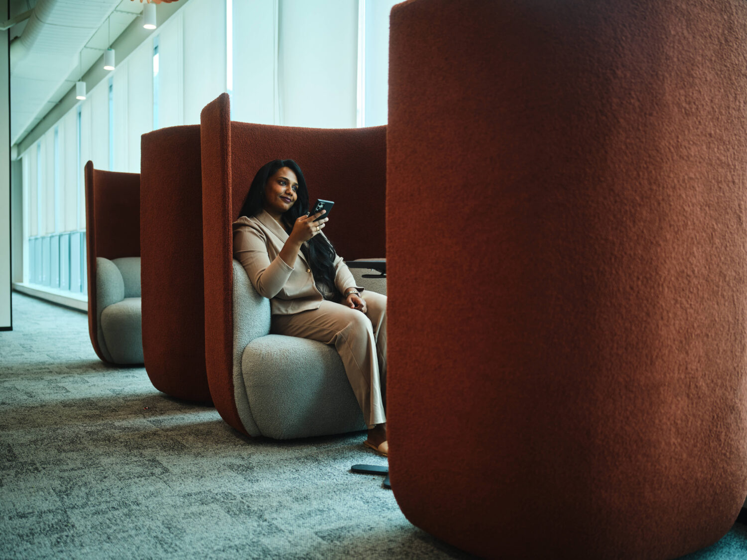 Lady sat in booth with her mobile phone in hand smiling.